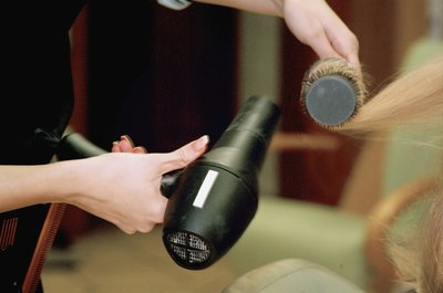 Medioimages/Photodisc/Photodisc/Getty Images A cosmetologist blow dries a client's hair.