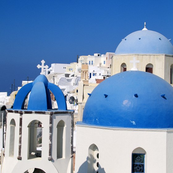 The blue-capped Santorini skyline towers over the surrounding Aegean Sea.