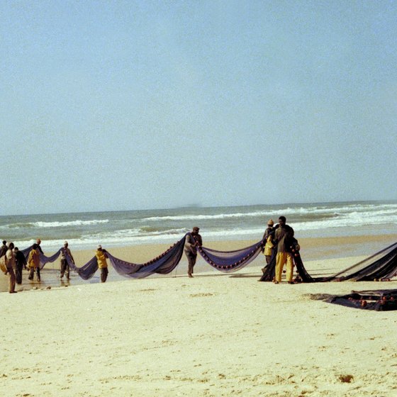 Locals wield fishing nets on a beach in Senegal.