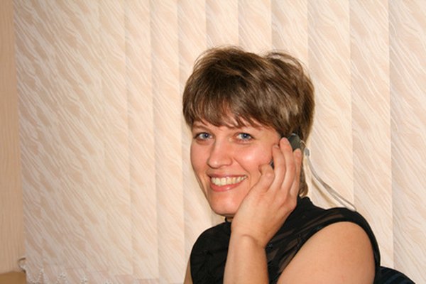 Beautiful business woman telephone. In office image by ssg from Fotolia.com Un comportamiento agradable ayuda a la recepcionista de oficina a dar una buena primera impresión de tu compañía.