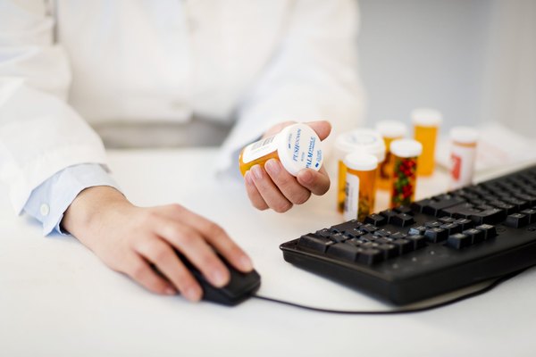 Pharmacist with pill bottles at computer