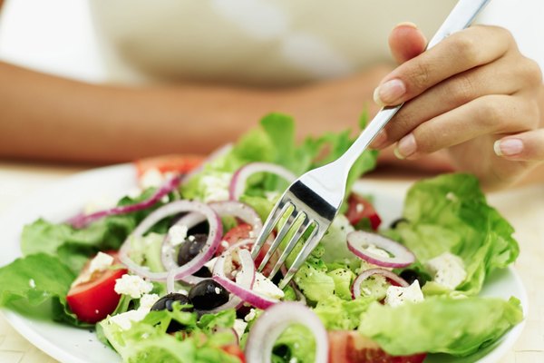Close-up of a person eating salad with a fork