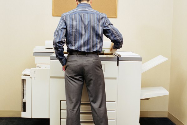 Male office worker using photocopying machine, rear view