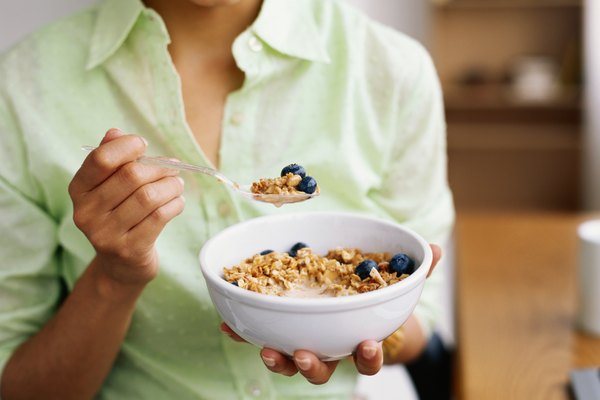 Woman holding bowl of cereal, mid section, close-up
