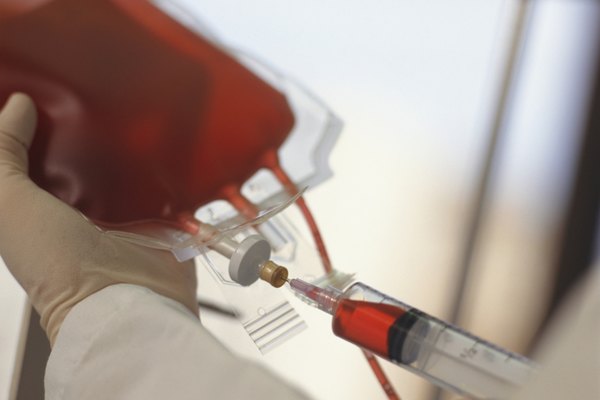 Technician drawing blood with syringe from blood bag, Close-up of hands