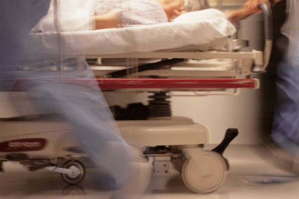 Medical staff moving patient on bed, in hospital corridor