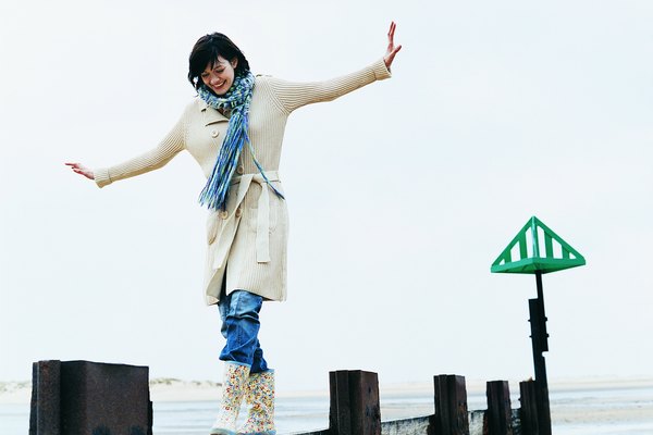 Woman Walks, Balancing With Her Arms Out on a Breakwater