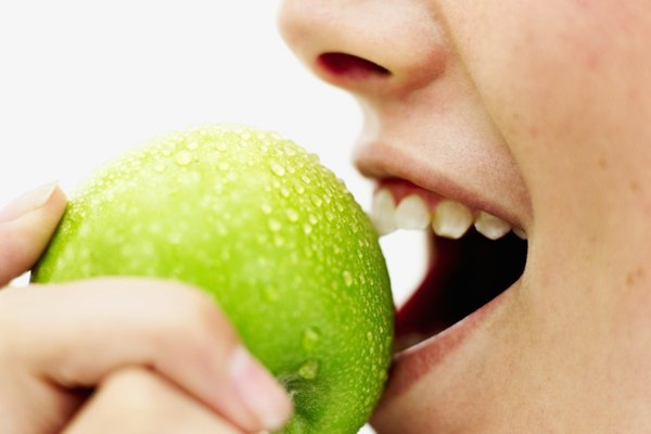 side view of a teenage girl (15-16) biting into a green apple