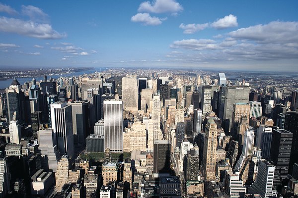 a shot of New York city from above with its skyscrapers and blue sky streaked with clouds