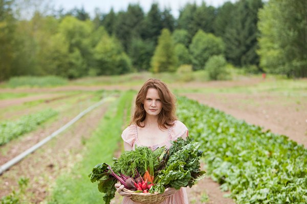Young woman on farm with basket of vegetable produce
