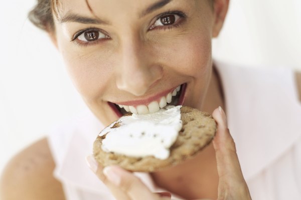 portrait of woman smiling biting a cracker with cheese