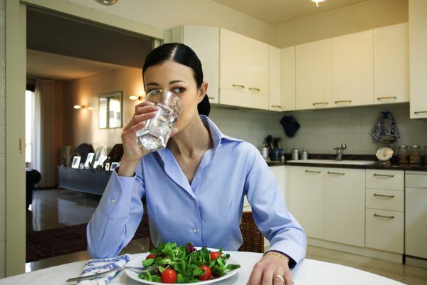 Woman with salad drinking water