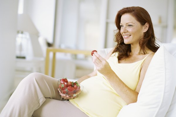 close-up of a pregnant woman holding a strawberry in her hand and smiling