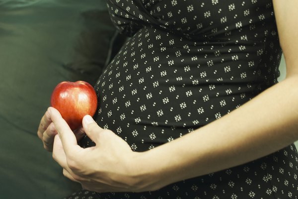 Cropped pregnant woman holding apple