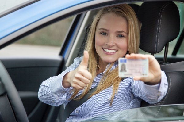 Attractive woman in car showing her drivers license