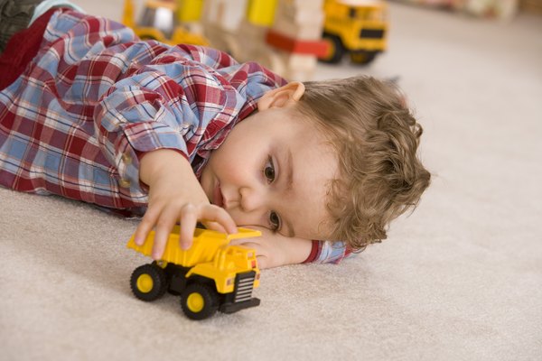 Young boy playing with yellow toy car.