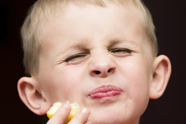 Boy making a funny face after eating a lemon.