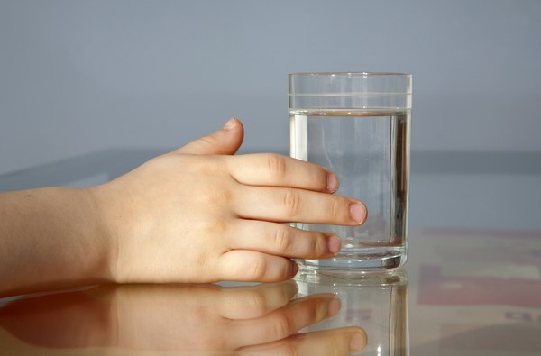 A child touches a glass of water.