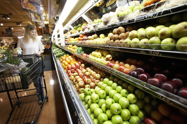 A woman is shopping in the produce section at the grocery store.