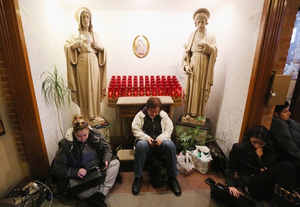 People rest and charge devices at a shelter for those affected by Superstorm Sandy at Saints Peter and Paul Church on November 1, 2012 in Hoboken, New Jersey.