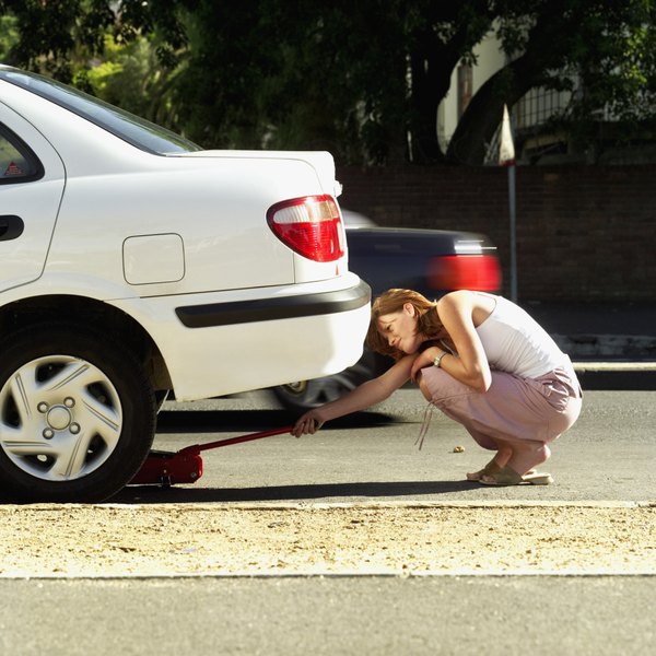 Woman about to lift automobile with hydraulic jack