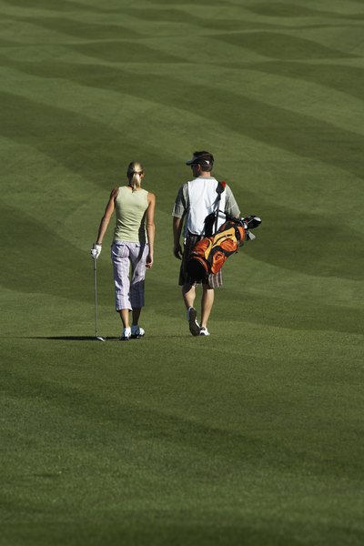 A player and her caddie walk down a well-groomed fairway.