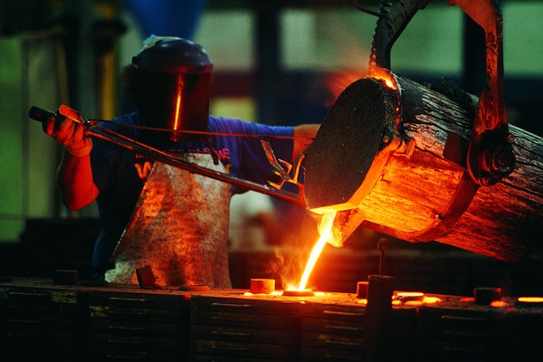 Foundry worker pouring liquid steel