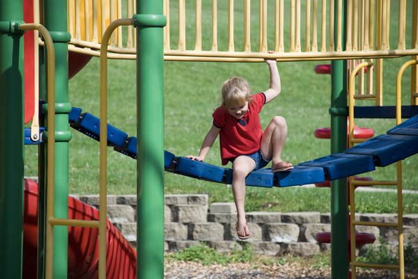 A child playing on a colorful jungle gym at the park.