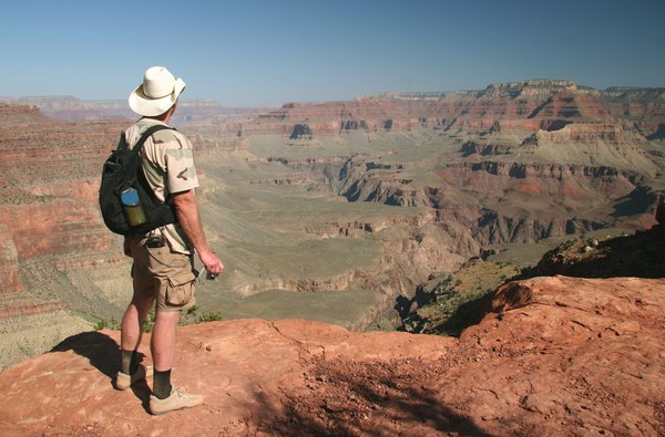 A man stands on the edge of a rock to view the Grand Canyon in Arizona.