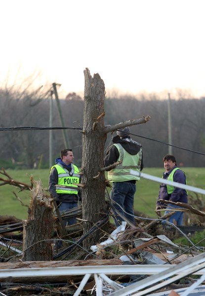 Police officers deal with live electrical wires due to a tornado.