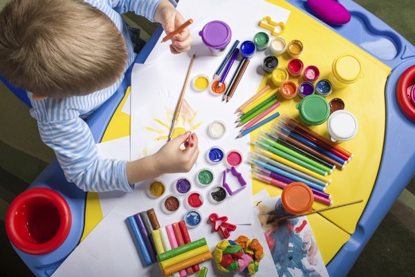 An overhead view of a young boy painting at an art table.