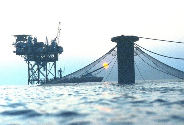 Covered salmon cage near an oil rig