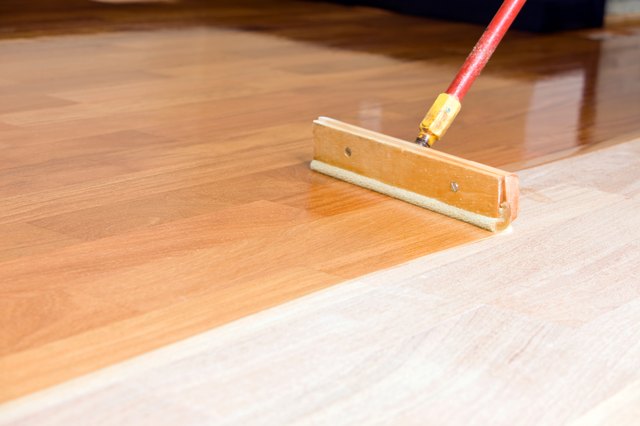 Squeegee Style Brush Applying Clear Polyurethane to Hardwood Floor
