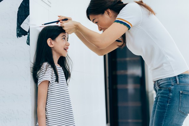 Mom measuring the growth of her daughter