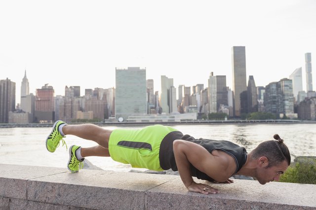 Young man doing body-weight push-up with leg lift