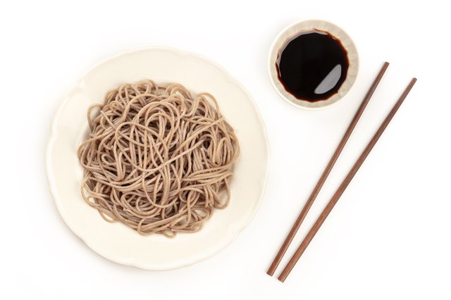 A plate of buckwheat noodles with chopsticks, shot from the top on a white background with a place for text