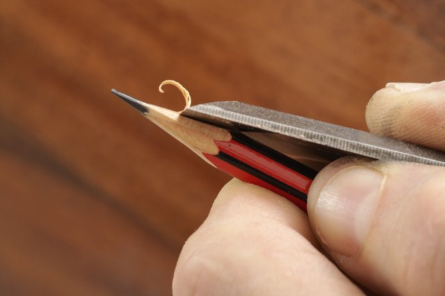 Young man sharpening pencil, close-up of fingers
