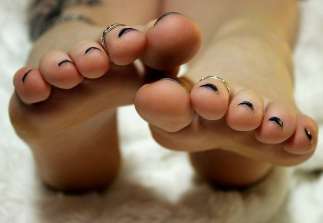 Low Section Of Woman With Painted Toenails On Bed