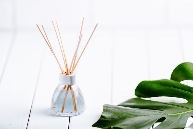 Air refresher bottle and leaf of a monstera with white background. Copyspace for your text