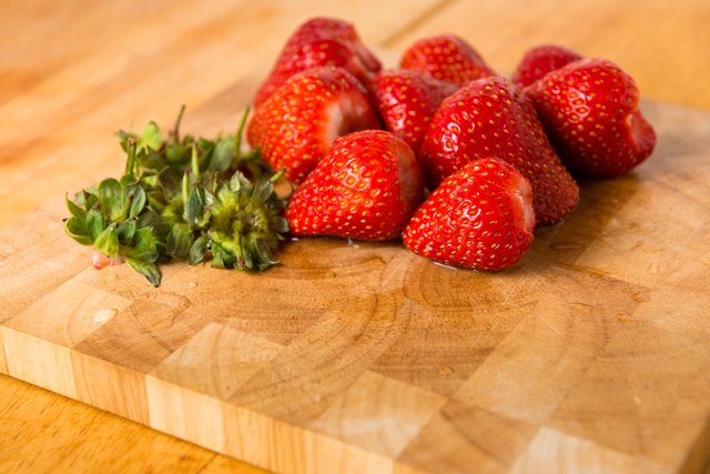 Strawberries and Stalks on Wooden Chopping Board