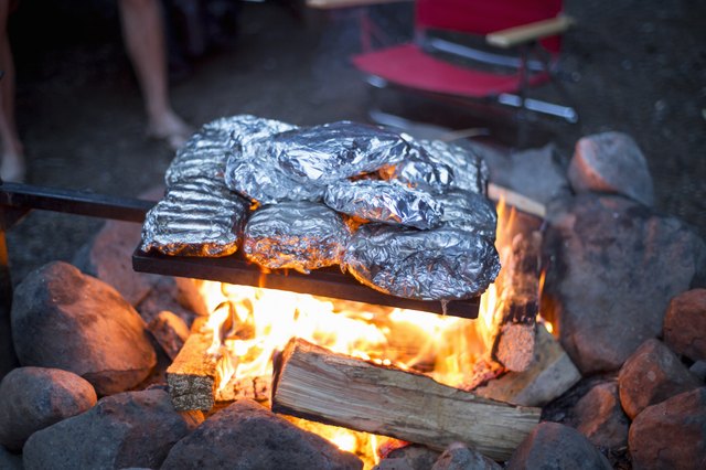 Food wrapped in tin foil cooking over campfire