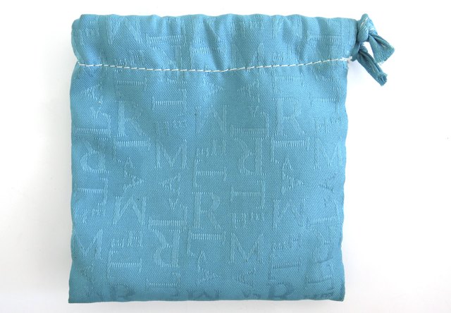 Isolated light blue 100% cotton bag. Canvas fabric with letters. Drawstring bag White background.