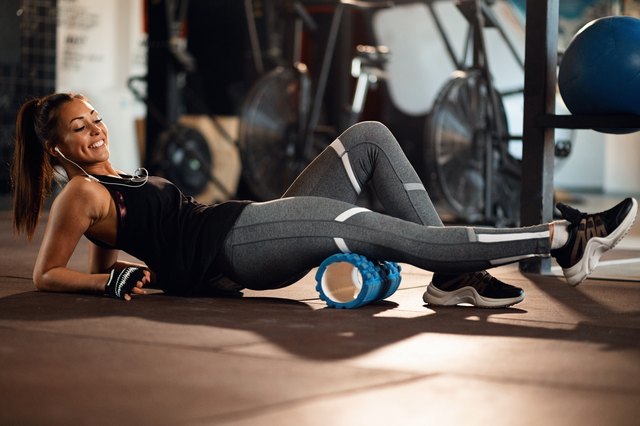 快乐的女运动员，在健身俱乐部发泡塑料滚轮锻炼。