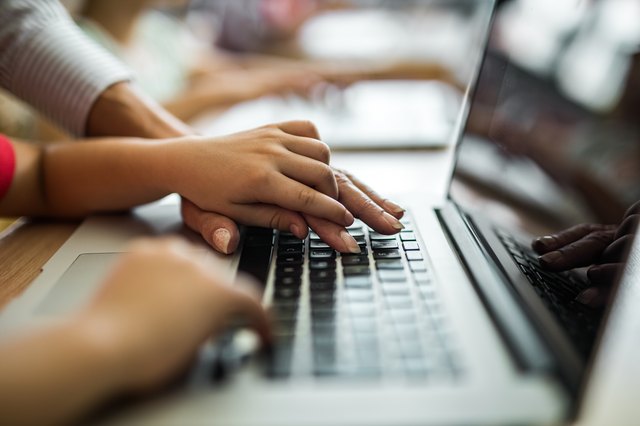 Close up of a child showing teacher how to use computer for e-learning.