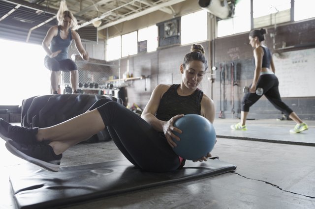 专注，坚强的女人在做坚韧不拔的健身房坐在实心球搓