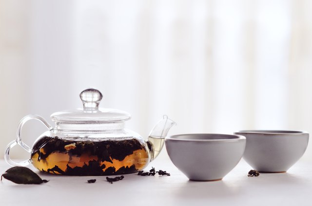 Black tea brewed in a transparent teapot with small cups on a white table. Concept tea ceremony, Chinese tradition, healthy drink