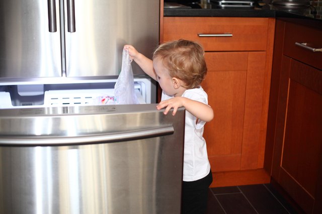 Little boy opened the freezer door and taking things out