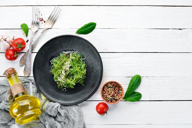 Seaweed salad in a black plate. Chuka wakame On the old background. Top view. Free space for your text.