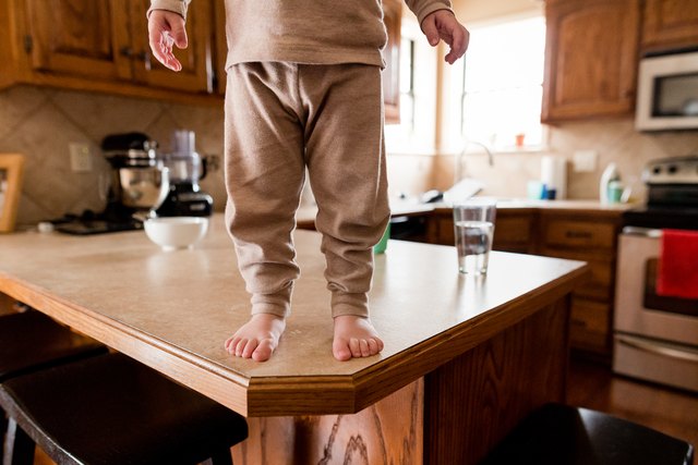 Low section of boy standing on wooden table in kitchen