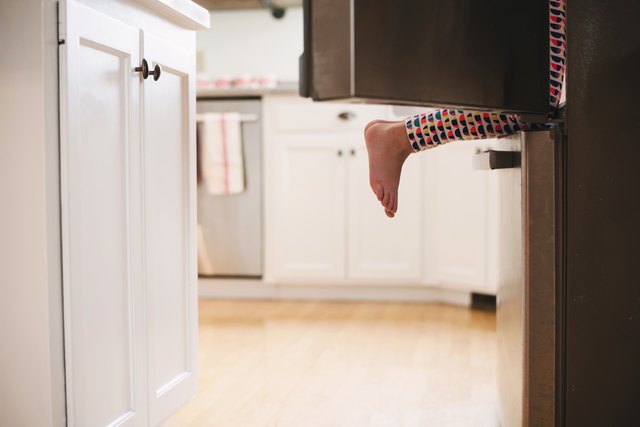 Young girl climbing into a refrigerator